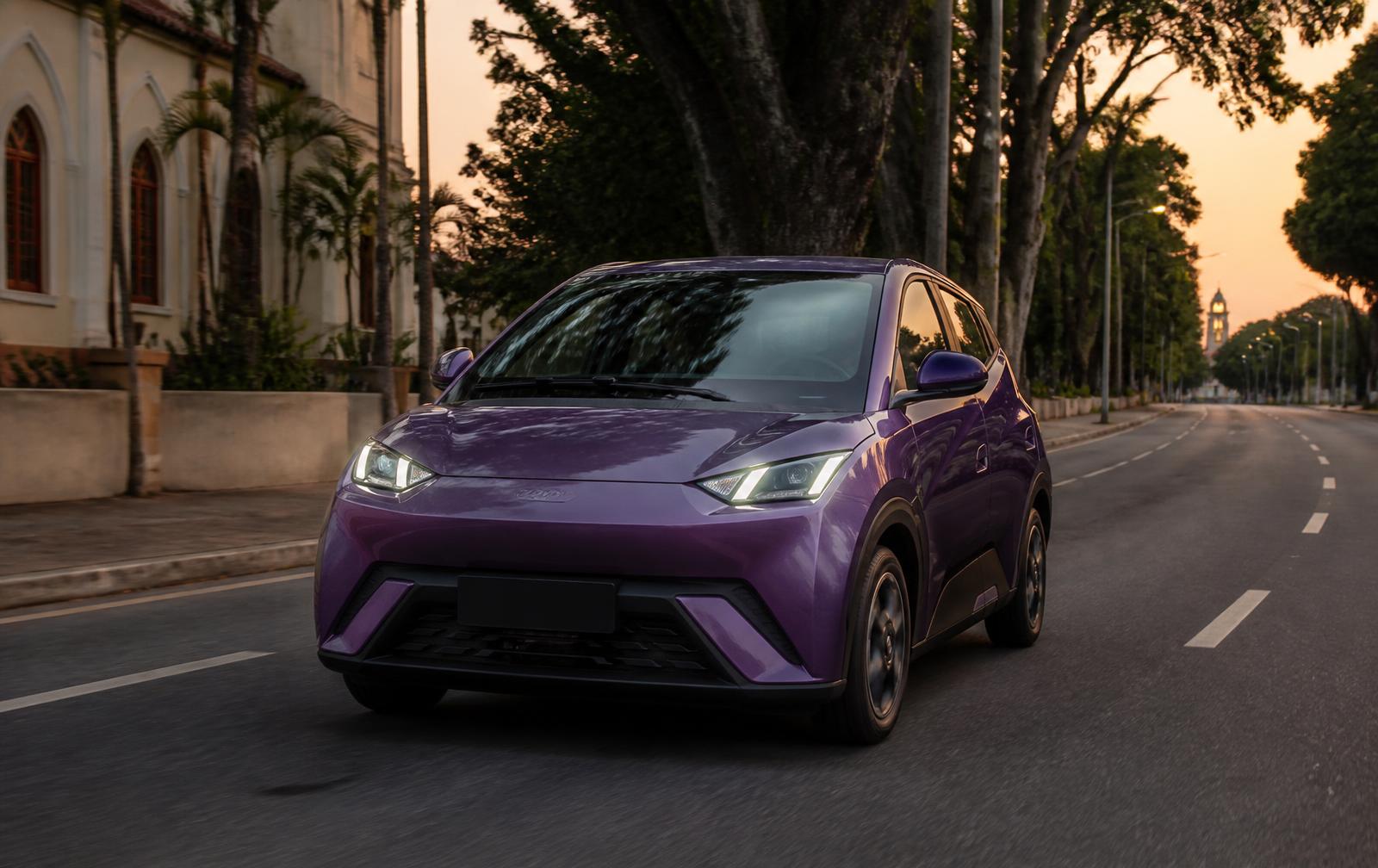 Carro roxo da Zeepy circulando por uma avenida da cidade ao anoitecer