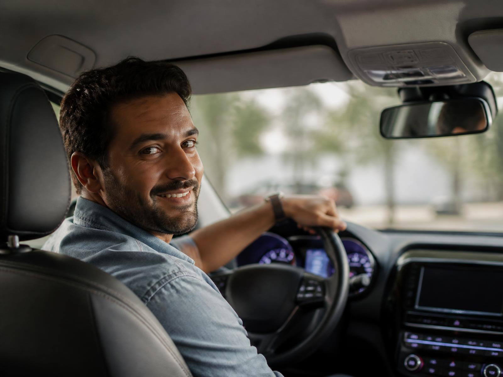 Motorista parceiro sorrindo ao volante de um carro limpo e confortável